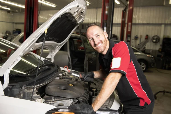 Mecánico guapo basado en el coche en taller de reparación de automóviles — Foto de Stock