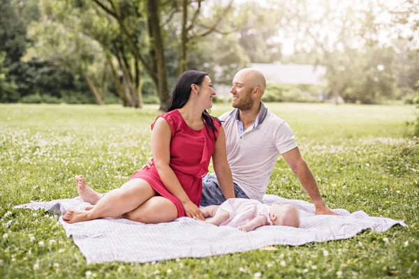 Familia feliz con la niña acostada en una manta — Foto de Stock