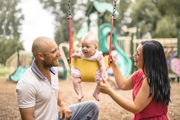 Cute adorable baby girl playing and swinging in swing in park — Stock Photo, Image
