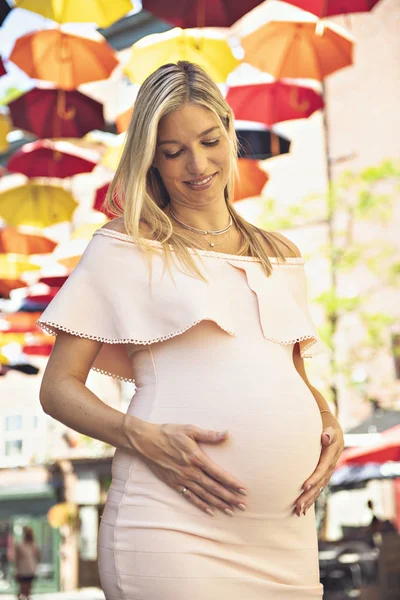 Mujer embarazada en la calle de la ciudad con paraguas en el fondo —  Fotos de Stock