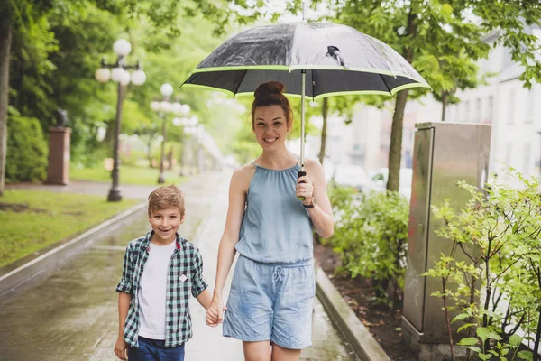 Mother and child on a rainy day in a park with umbrella — Stock Photo, Image