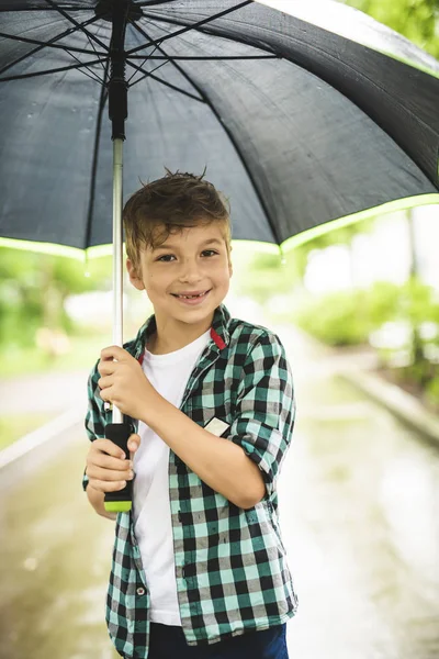 Söt pojke, promenader i en park en regnig dag — Stockfoto