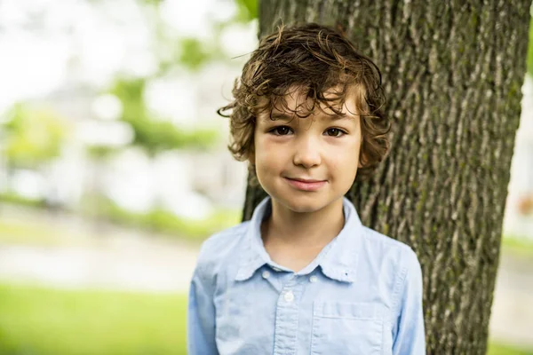 Söt kaukasiska pojke gärna nära ett träd — Stockfoto