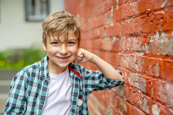 Adorable cute boy staing near a red brick wall — Stock Photo, Image