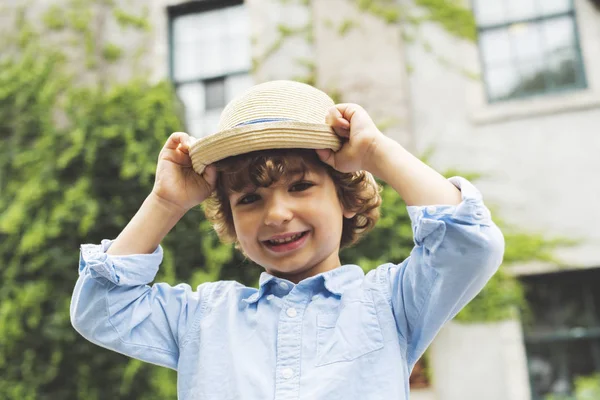 Portret van schattige kleine jongen permanent in stad straat met zijn hoed — Stockfoto