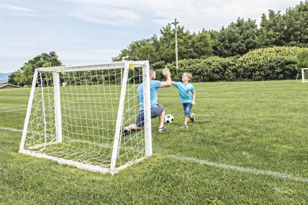 Άντρας με παιδί παίζει ποδόσφαιρο έξω στο γήπεδο — Φωτογραφία Αρχείου