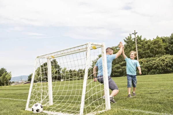 Man with child playing football outside on field — Stock Photo, Image