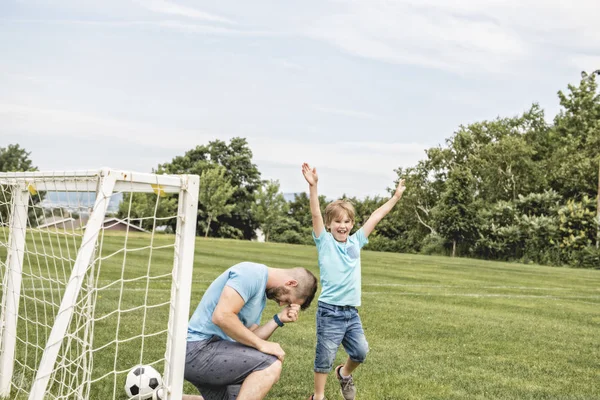 Man with child playing football outside on field — Stock Photo, Image
