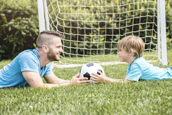 Hombre con niño jugando al fútbol afuera en el campo — Foto de Stock