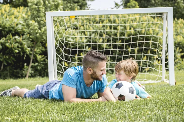 Uomo con bambino che gioca a calcio fuori sul campo — Foto Stock