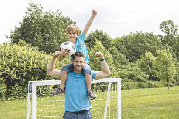 Man med barn spelar fotboll utanför på planen — Stockfoto