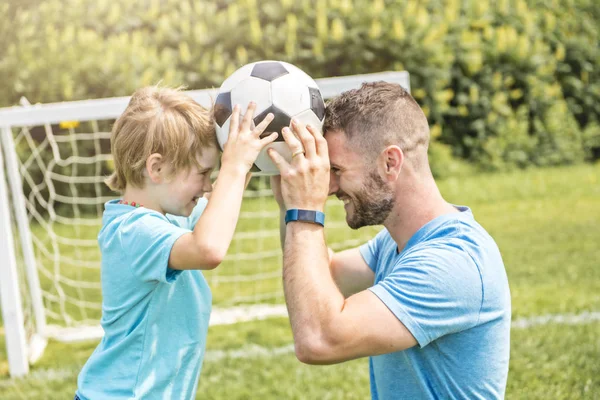 Man met kind voetballen buiten op het veld — Stockfoto