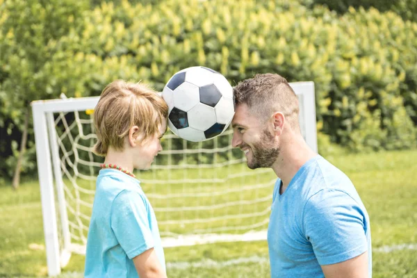 Hombre con niño jugando al fútbol afuera en el campo — Foto de Stock