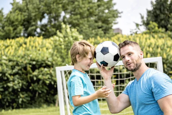 Man med barn spelar fotboll utanför på planen — Stockfoto