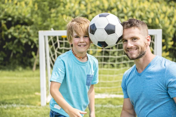 Hombre con niño jugando al fútbol afuera en el campo —  Fotos de Stock