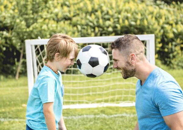 Hombre con niño jugando al fútbol afuera en el campo —  Fotos de Stock