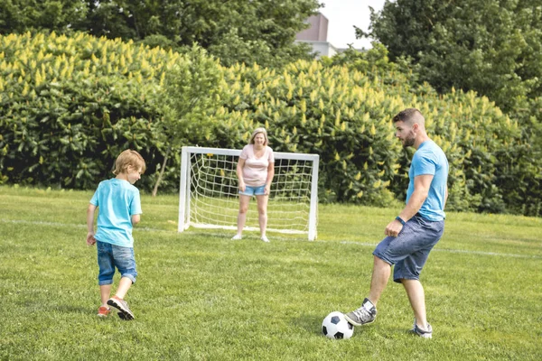 Homem com criança jogando futebol fora no campo — Fotografia de Stock