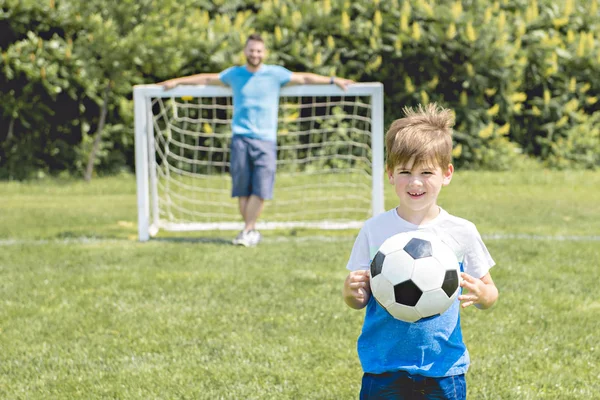 Hombre con niño jugando al fútbol afuera en el campo —  Fotos de Stock