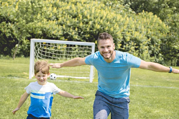 Hombre con niño jugando al fútbol afuera en el campo — Foto de Stock