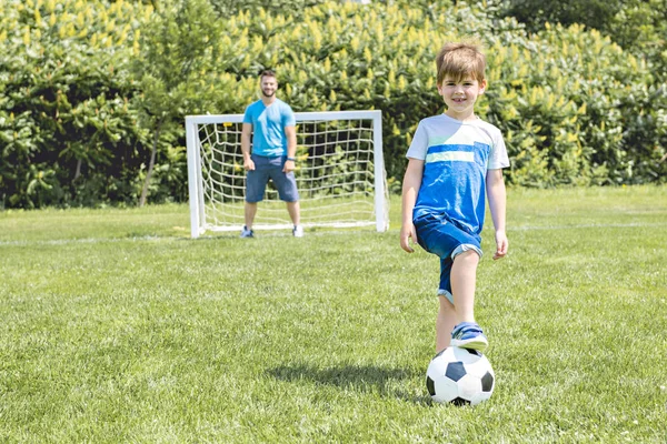 Man with child playing football outside on field — Stock Photo, Image