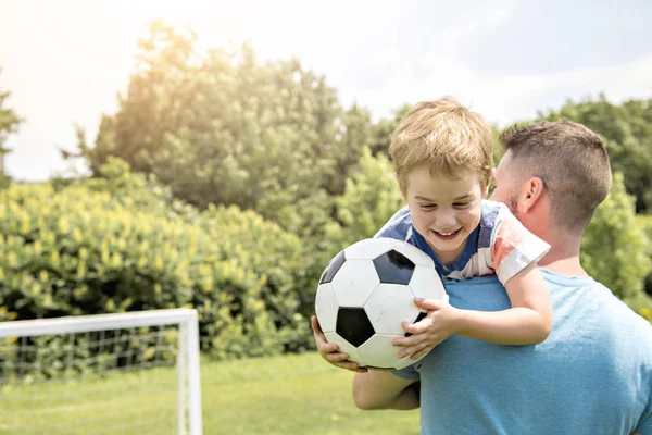 Man met kind voetballen buiten op het veld — Stockfoto