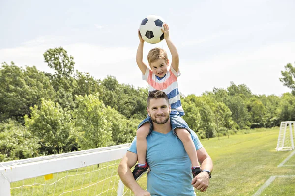 Uomo con bambino che gioca a calcio fuori sul campo — Foto Stock