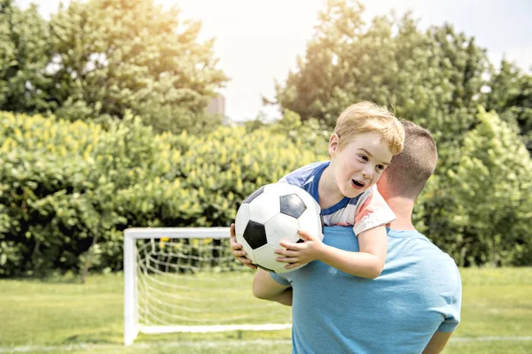 Uomo con bambino che gioca a calcio fuori sul campo — Foto Stock