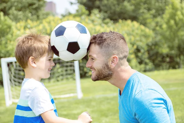 Man met kind voetballen buiten op het veld — Stockfoto