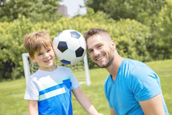 Uomo con bambino che gioca a calcio fuori sul campo — Foto Stock