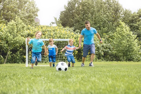 Man with child playing football outside on field — Stock Photo, Image