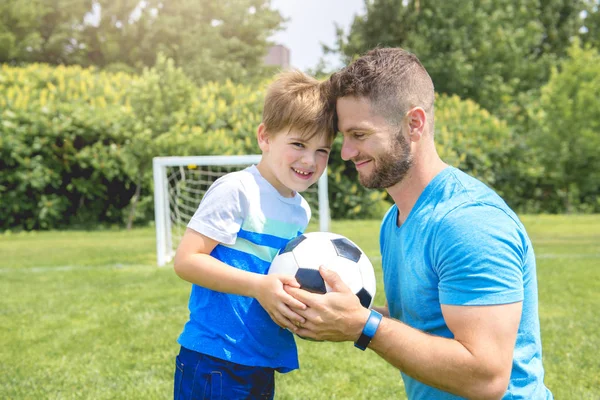 Uomo con bambino che gioca a calcio fuori sul campo — Foto Stock