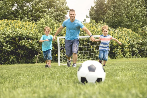 Man med barn spelar fotboll utanför på planen — Stockfoto