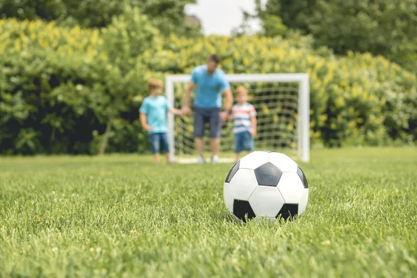 Man with child playing football outside on field — Stock Photo, Image