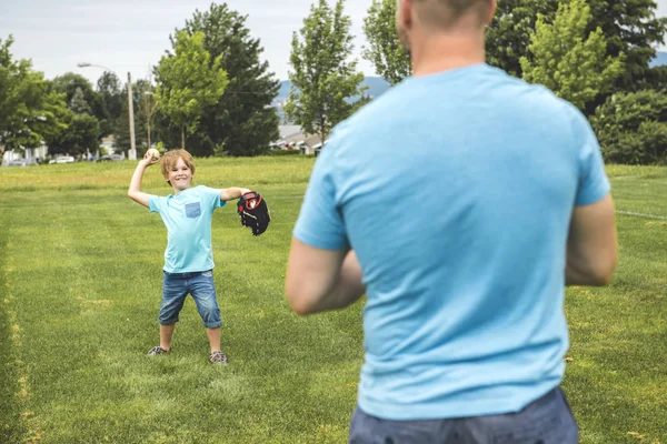 Stilig pappa med sin lilla söta sol spelar baseball på gröna gräsbevuxna gräsmatta — Stockfoto