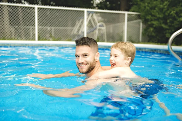 Lindo niño aprendiendo a nadar con los padres en la piscina —  Fotos de Stock