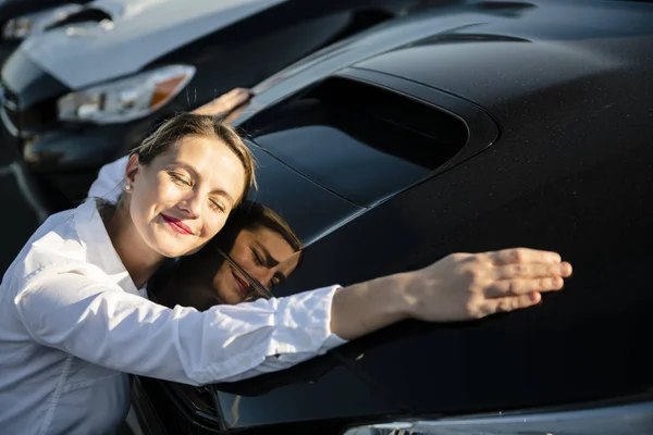 Γυναίκα αυτοκίνητο πωλητής που αγκαλιάζει το αυτοκίνητο στο γκαράζ — Φωτογραφία Αρχείου