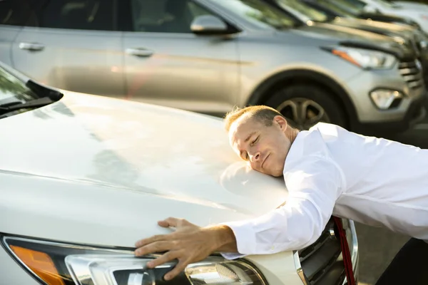 Vendedor de coches hombre abrazando coche en el garaje — Foto de Stock