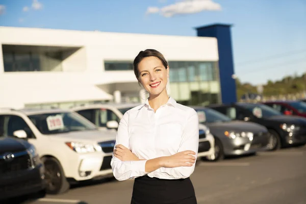 Alquiler de coches de mujer joven frente al garaje con coches en el fondo — Foto de Stock