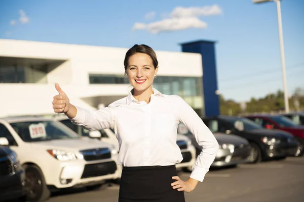 Jonge vrouw autoverhuur voor garage met auto's op de achtergrond — Stockfoto