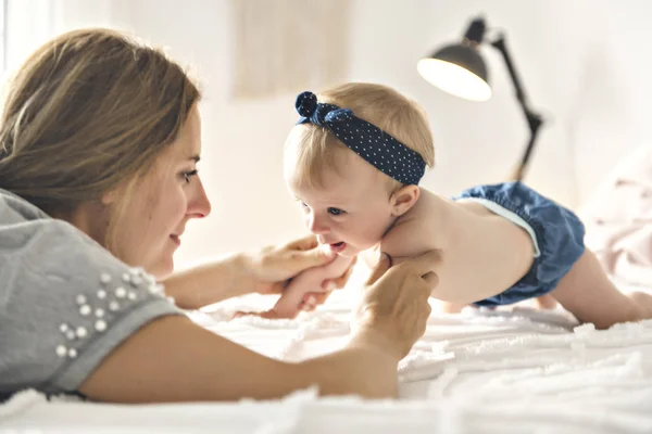 Mother and baby girl on a white bed — Stock Photo, Image