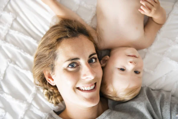 Mother and baby girl on a white bed — Stock Photo, Image