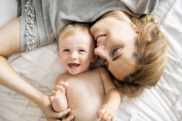 Mother and baby girl on a white bed — Stock Photo, Image