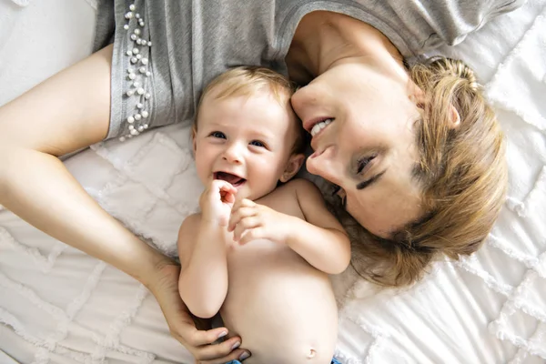 Mãe e bebê menina em uma cama branca — Fotografia de Stock