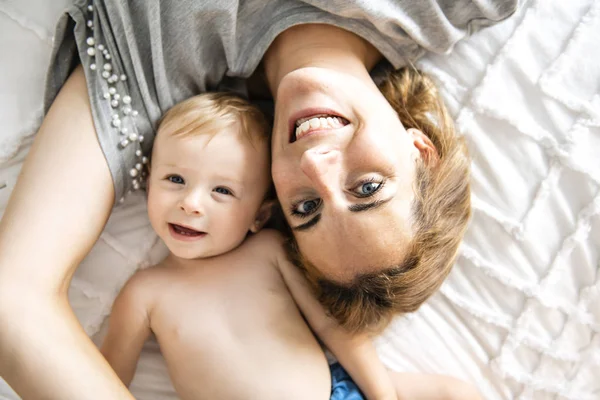Mother and baby girl on a white bed — Stock Photo, Image