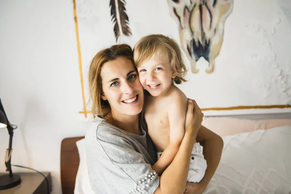 Junge Mutter mit ihrem kleinen Sohn entspannt sich und spielt am Wochenende zusammen im Bett — Stockfoto