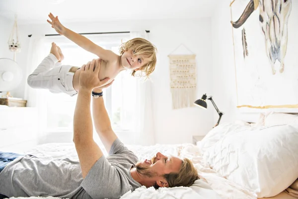 幸せな父の自宅のベッドに彼の少年と遊ぶ — ストック写真