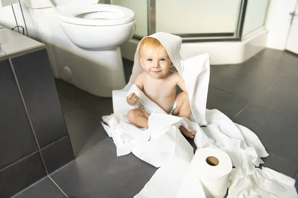 Toddler ripping up toilet paper in bathroom — Stock Photo, Image