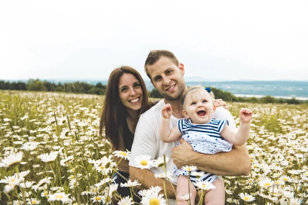 Kızın ve onun baba ve anne açık havada papatya çiçekler alanında zevk — Stok fotoğraf
