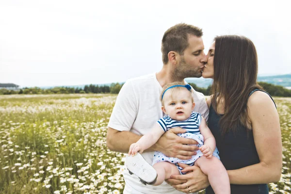 Kızın ve onun baba ve anne açık havada papatya çiçekler alanında zevk — Stok fotoğraf