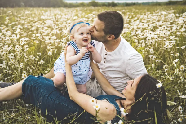 小さな女の赤ちゃんと彼の家族は、デイジーの花のフィールドでのアウトドアを楽しむ — ストック写真